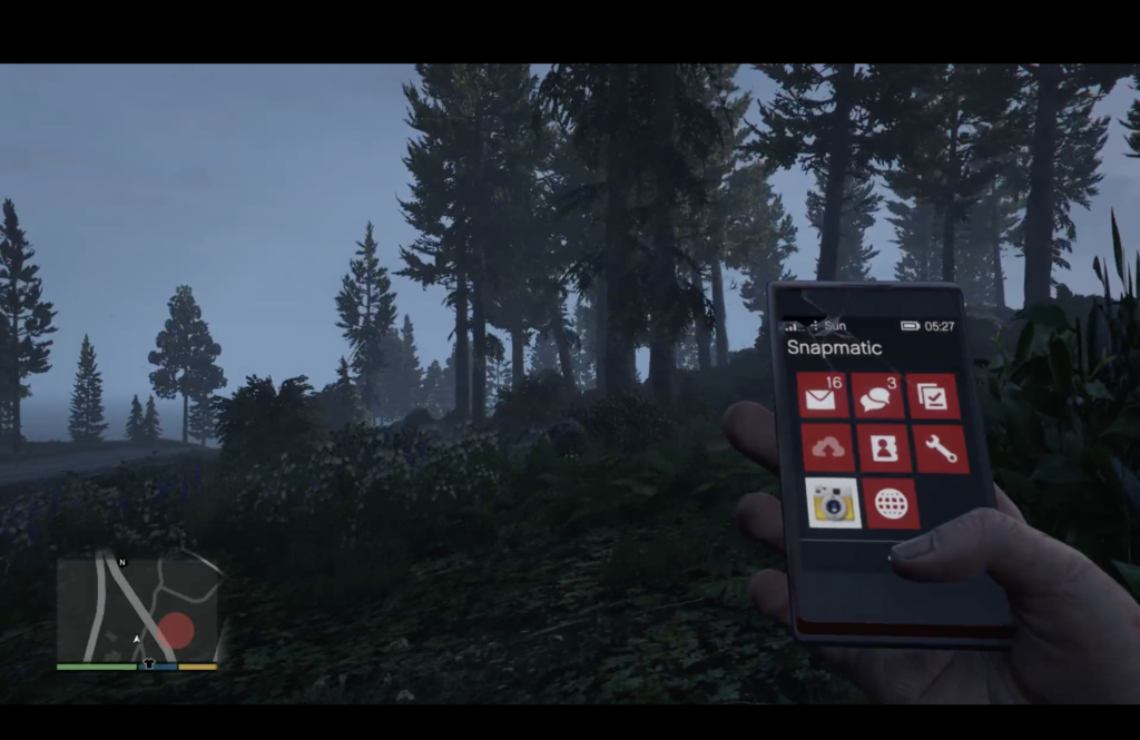 The image shows a screenshot from Grand Theft Auto V. From a first person perspective you look at a rural, forest area. The hand of your avatar holds a simulated smartphone with the snapmatic app opened. Workshop: The Photographer's Guide to Los Santos