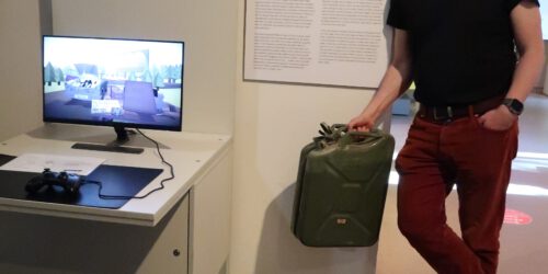 Picture shows Sebastian Möring holding a petrol can and standing next to the personal classic station in Computerspielemuseum Berlin